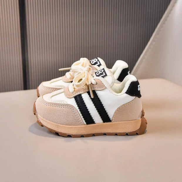 Two kids' sneakers with white uppers, black stripes, beige suede, and cream laces.